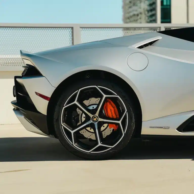 Close-up of the rear wheel and bright orange brake caliper on a silver Lamborghini Huracán EVO Spyder.
