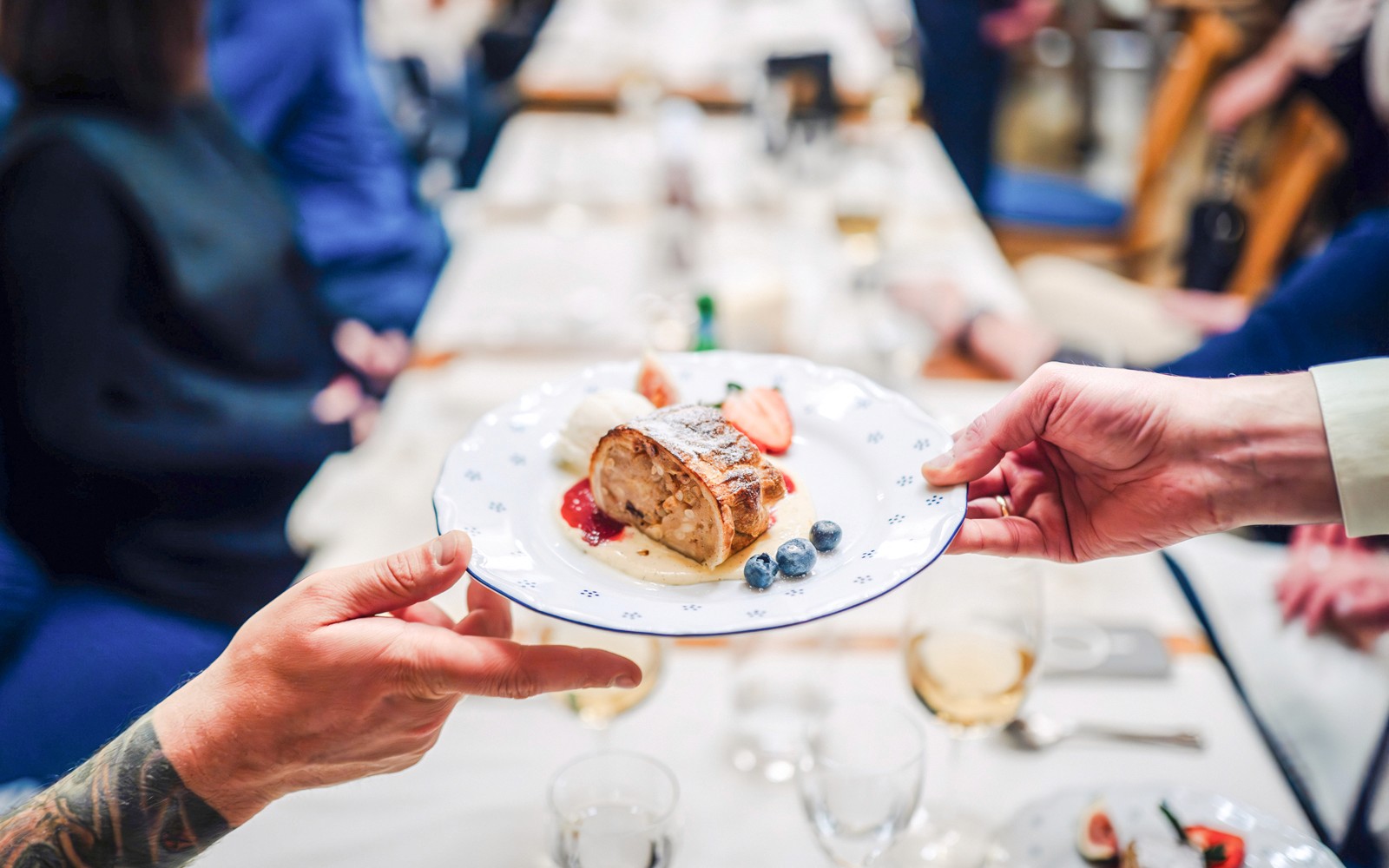 Sepiring apel strudel dengan beri yang sedang dinikmati bersama oleh dua orang di meja makan.