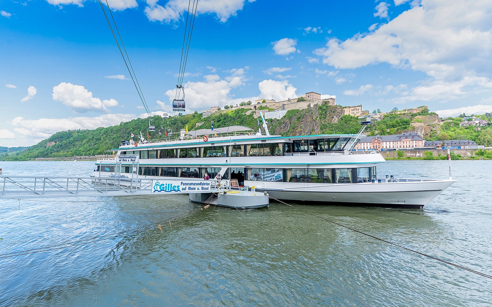 Koblenz sightseeing cruise boat on the Rhine River with Ehrenbreitstein Fortress in the background.