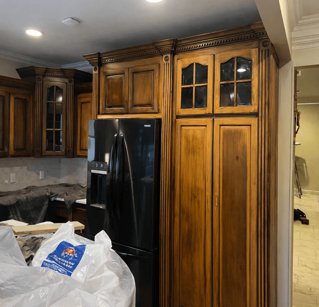 A modern, luxury beachfront villa with large glass windows and balconies overlooks a rocky shoreline, surrounded by palm trees at sunset.