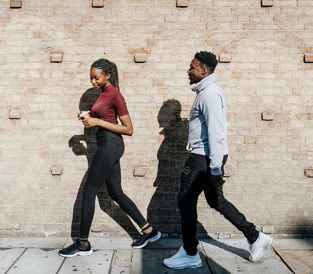 Two people walking on the pavement