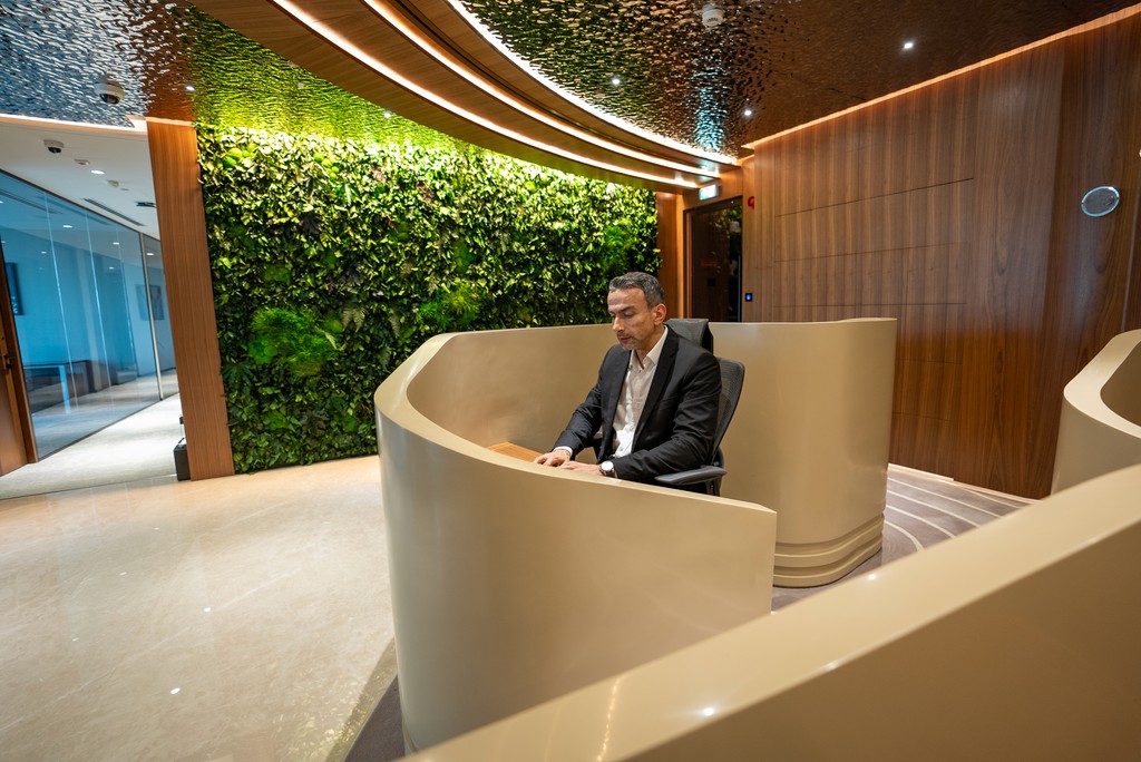 Professional at Office Square’s serviced office in Abu Dhabi, set against a curved desk and vertical garden wall.