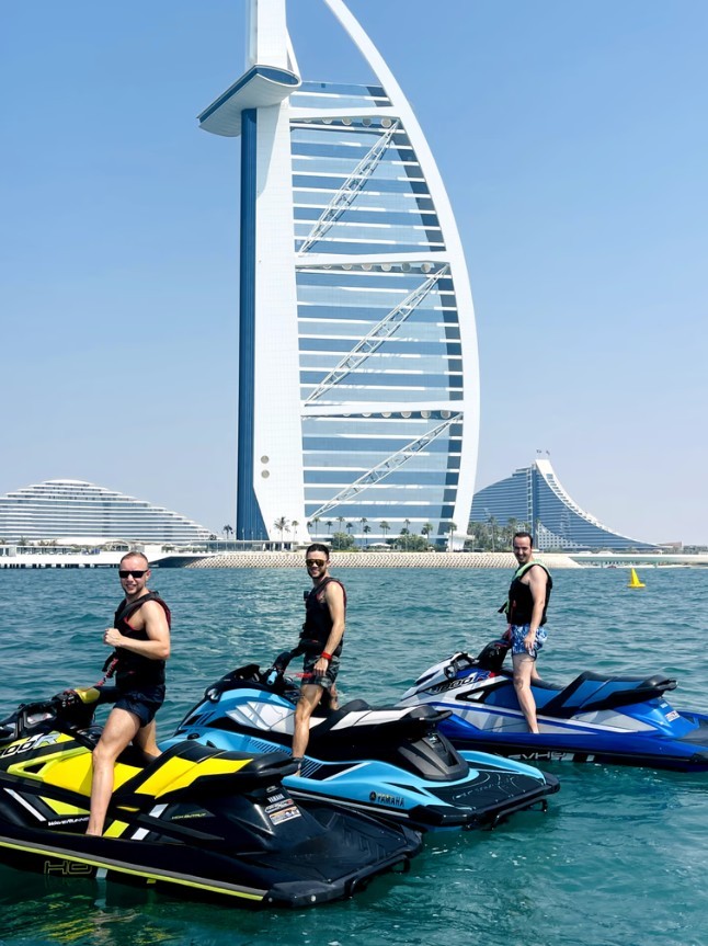 People on a Jet Ski Tour posing with the Burj al Arab in view.