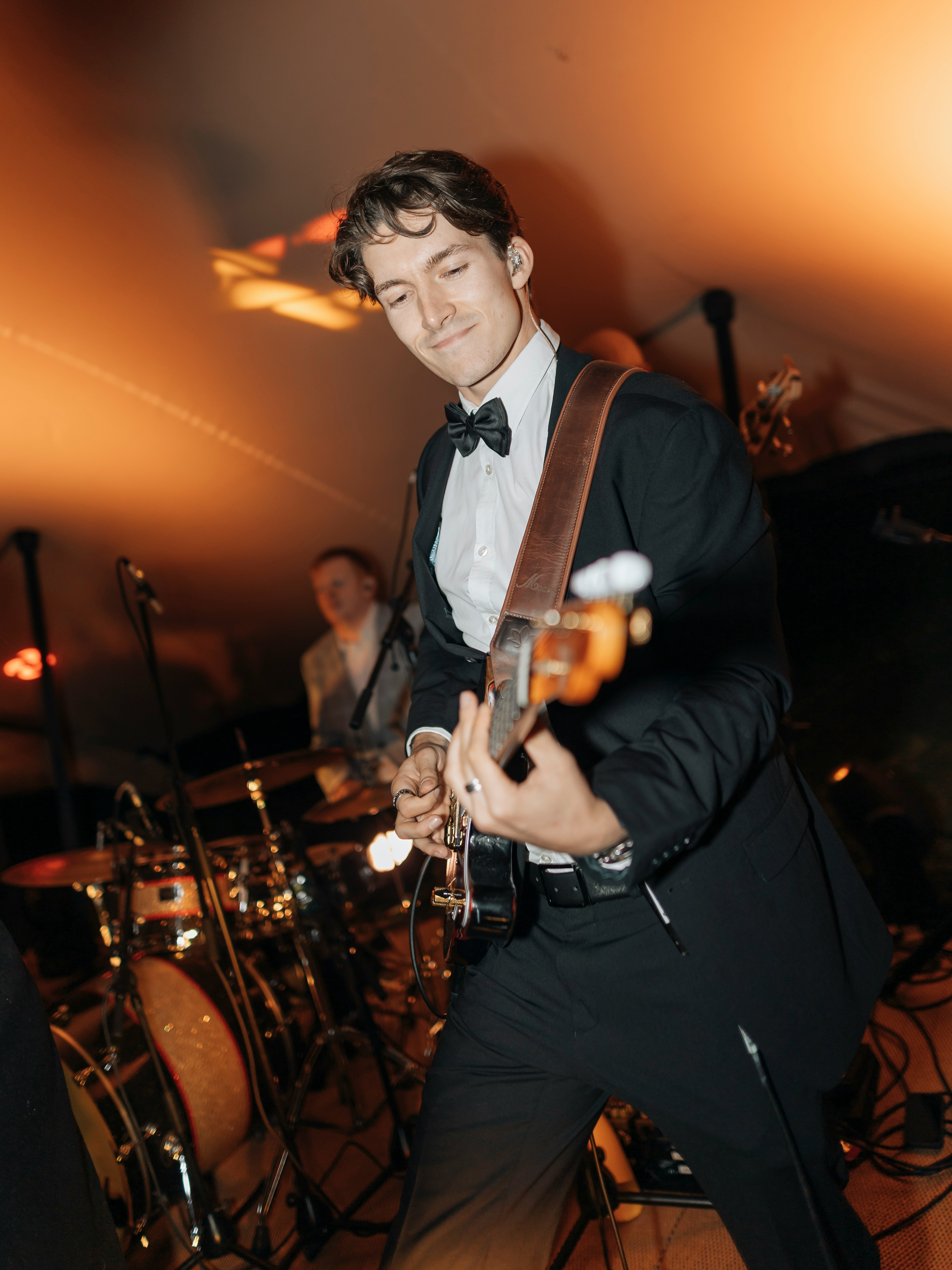 Man in a tuxedo playing guitar on stage