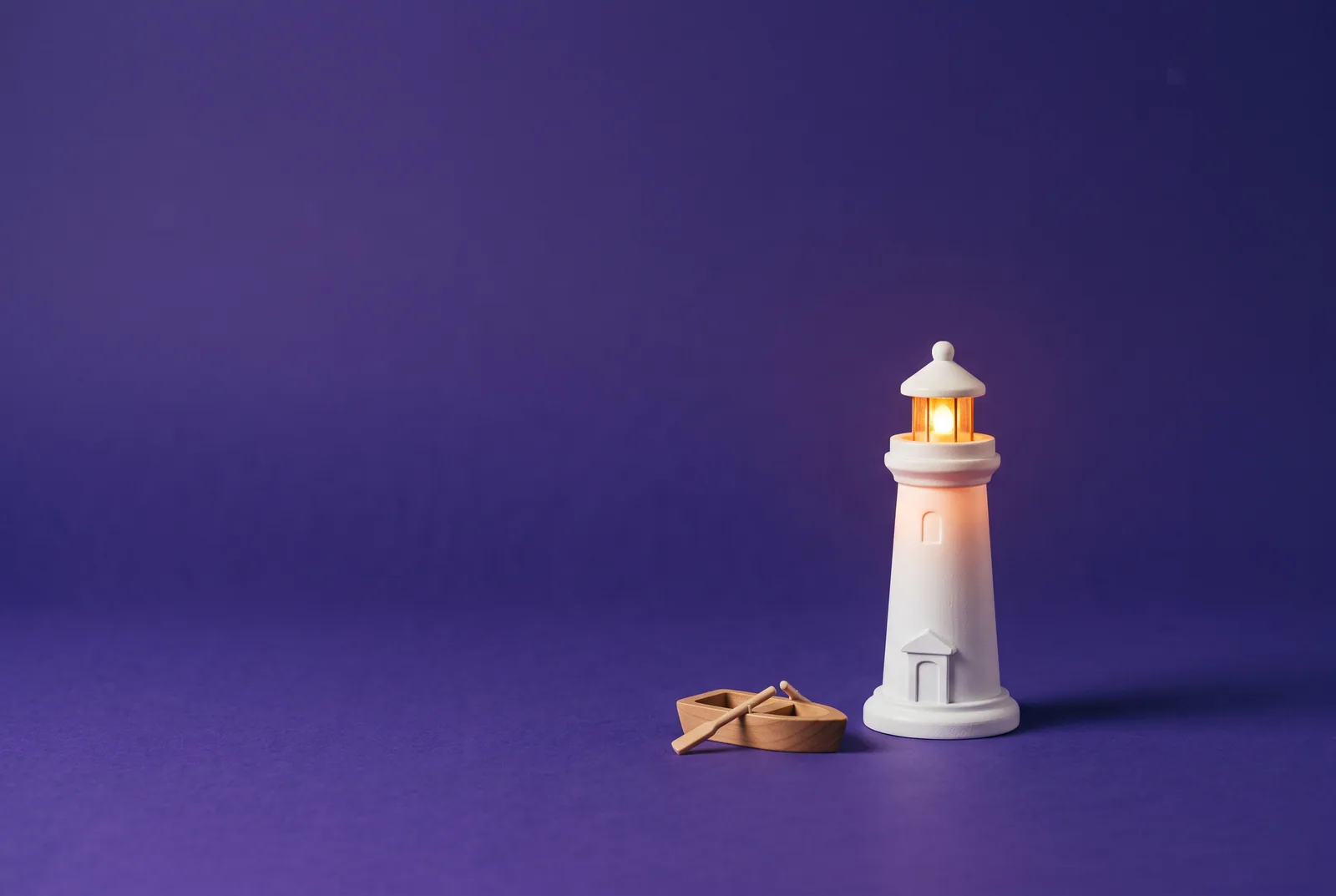A small glowing toy lighthouse beside a wooden rowboat, when to get more help as you quit porn as a teenager