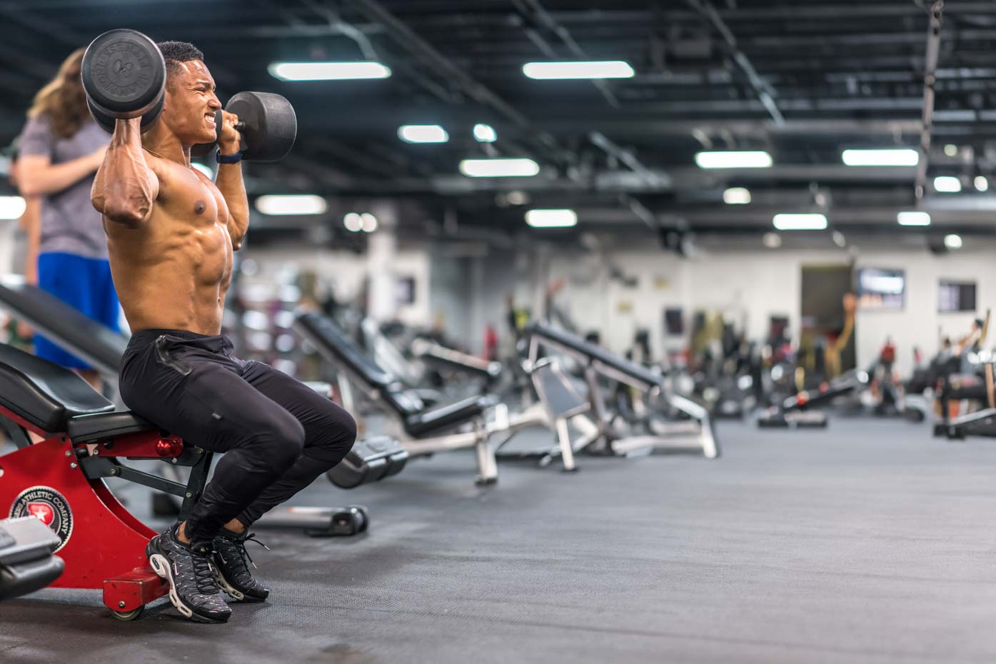 topless man in black shorts sitting on black and silver barbell