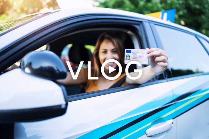 A person walks in front of large stone arches with dark doors, flanked by tall columns, in a historic building.