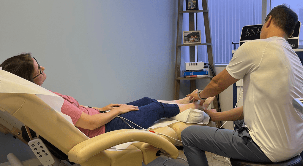 Image of a patient sitting in a chair with a doctor assessing her foot