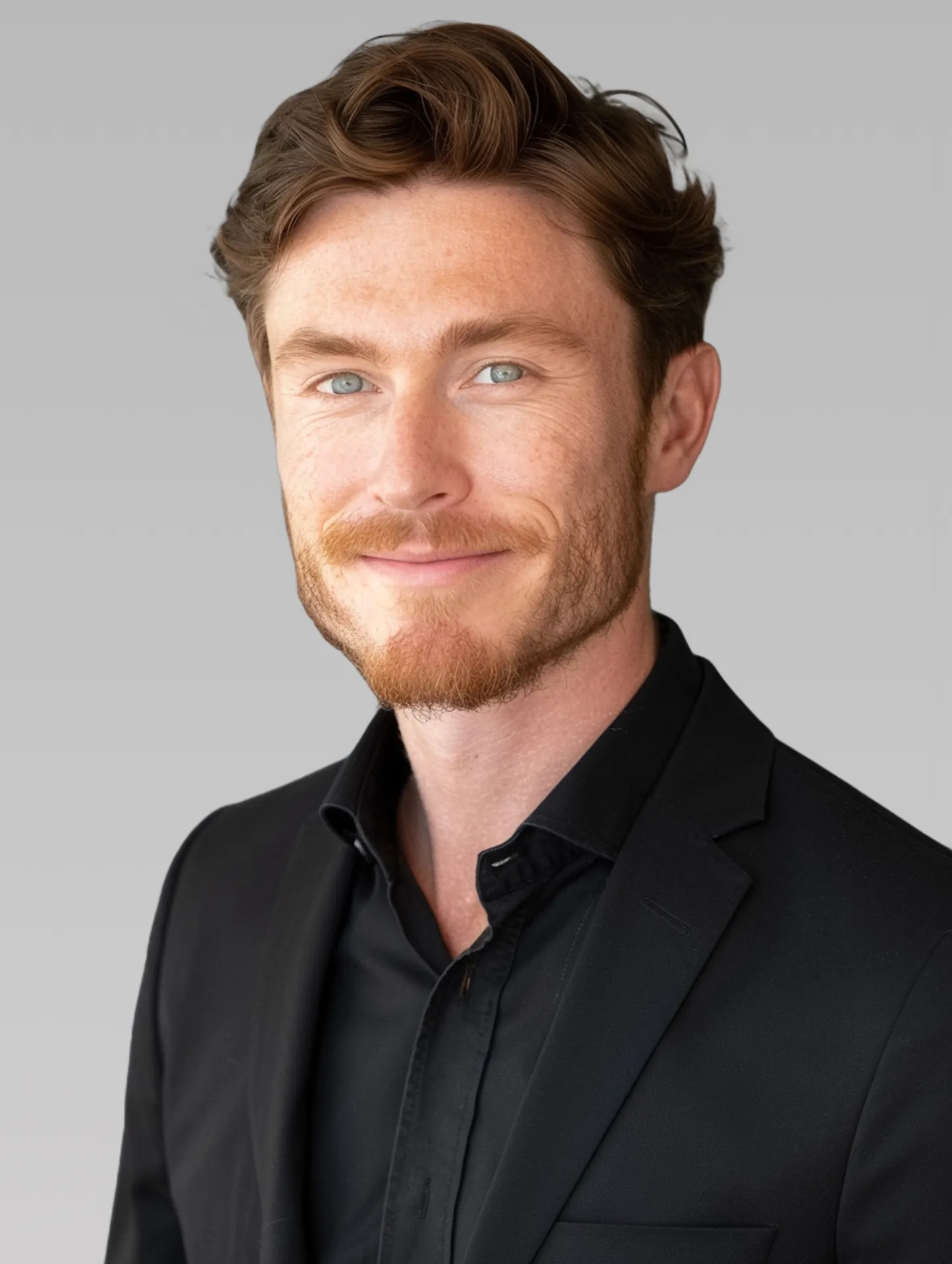 Professional portrait of a man in a suit with a neutral gray background, showcasing a clean and formal appearance.