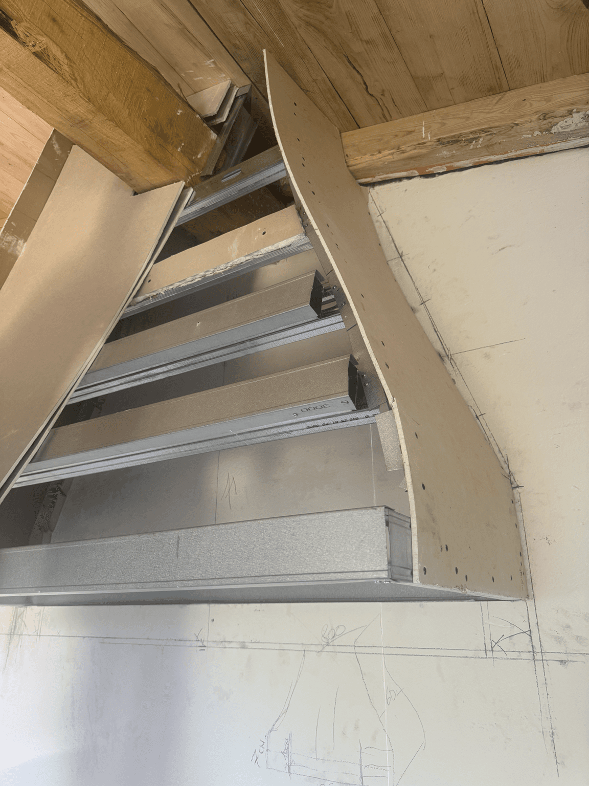 Ossature métallique et plaques de plâtre découpées pendant la construction d’une hotte de cuisine sur mesure