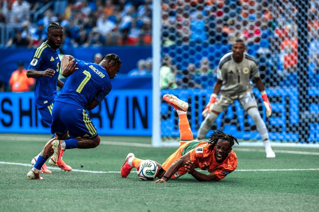 An Ivory Coast attacker reaches for the ball near goal as Curaçao's Juninho Bacuna runs past during the World Cup match