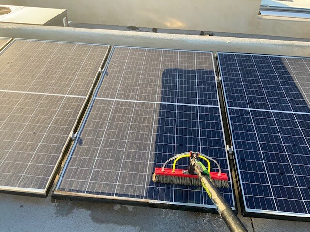 A person cleaning solar panel with a tool