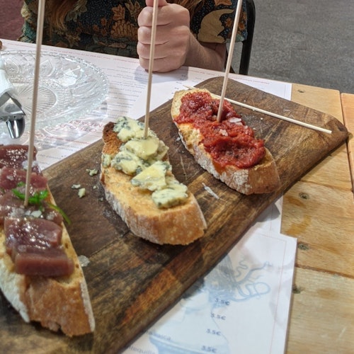 Three slices of bread topped with different toppings on a wooden board. A person's hand is visible in the background.
