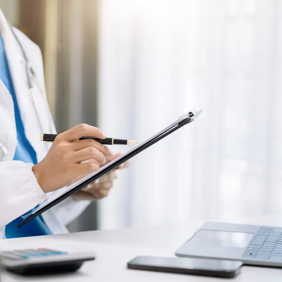 AI for doctors enhances workflow as a healthcare professional in a white coat reviews a clipboard near a laptop