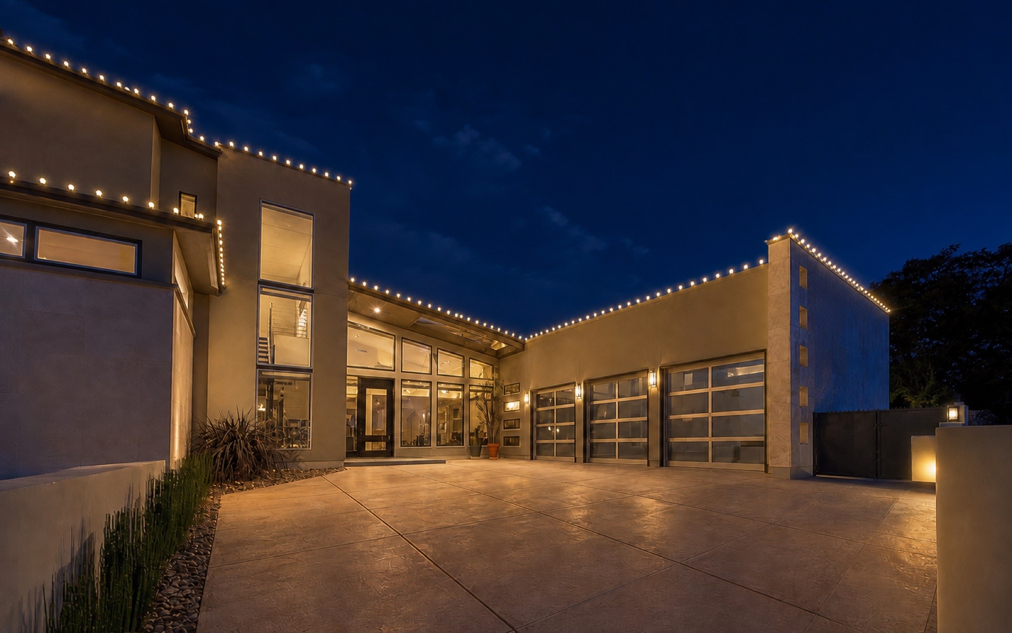 Modern courtyard lit with permanent roofline lighting