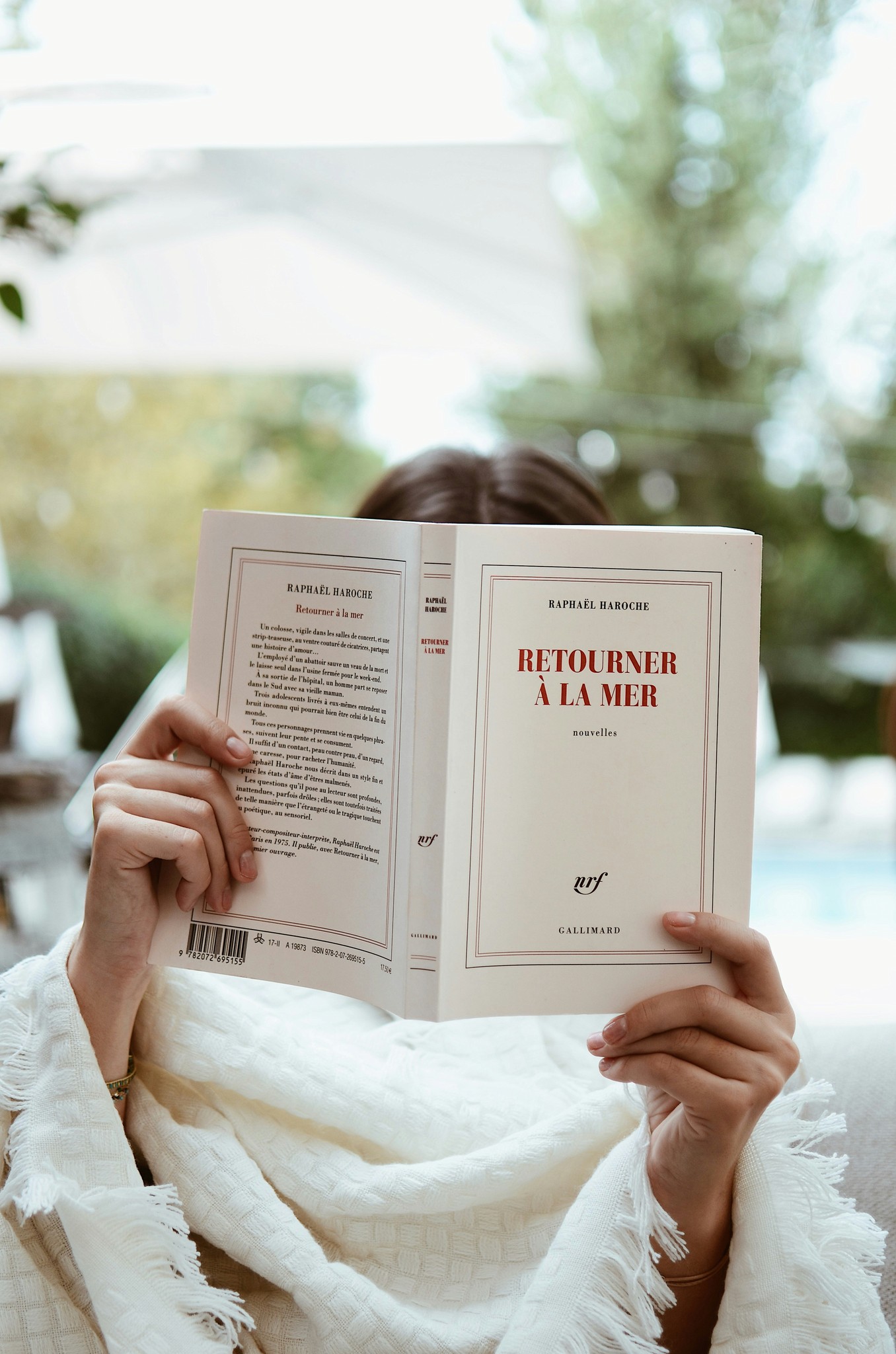 A woman sitting on a couch reading a book