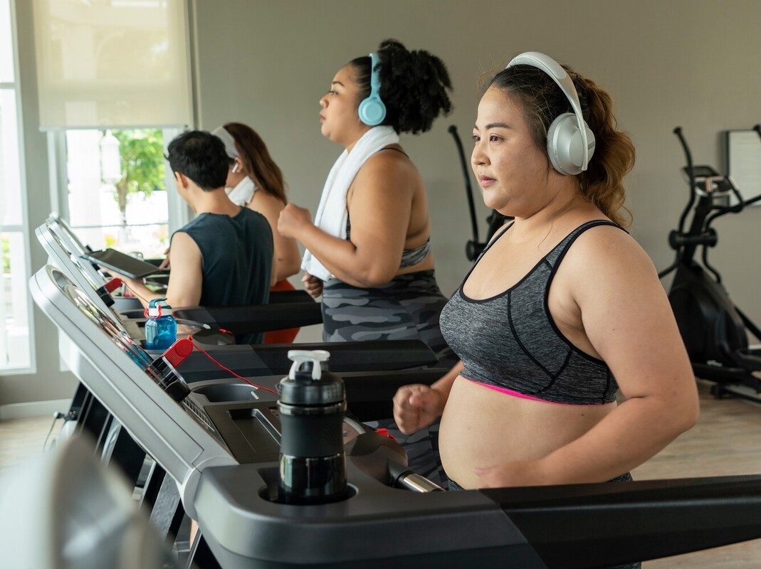 woman running to lose weight on a treadmill in the gym with headphones on at the start of her weight loss journey