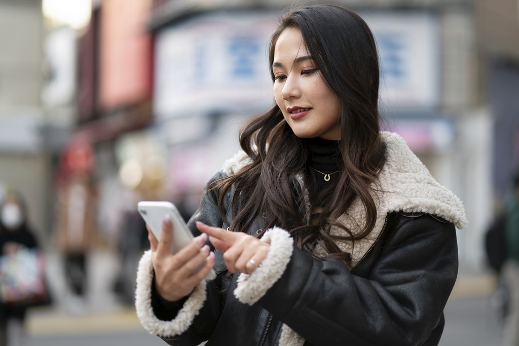 Woman traveler smiling at their phone while traveling in Japan
