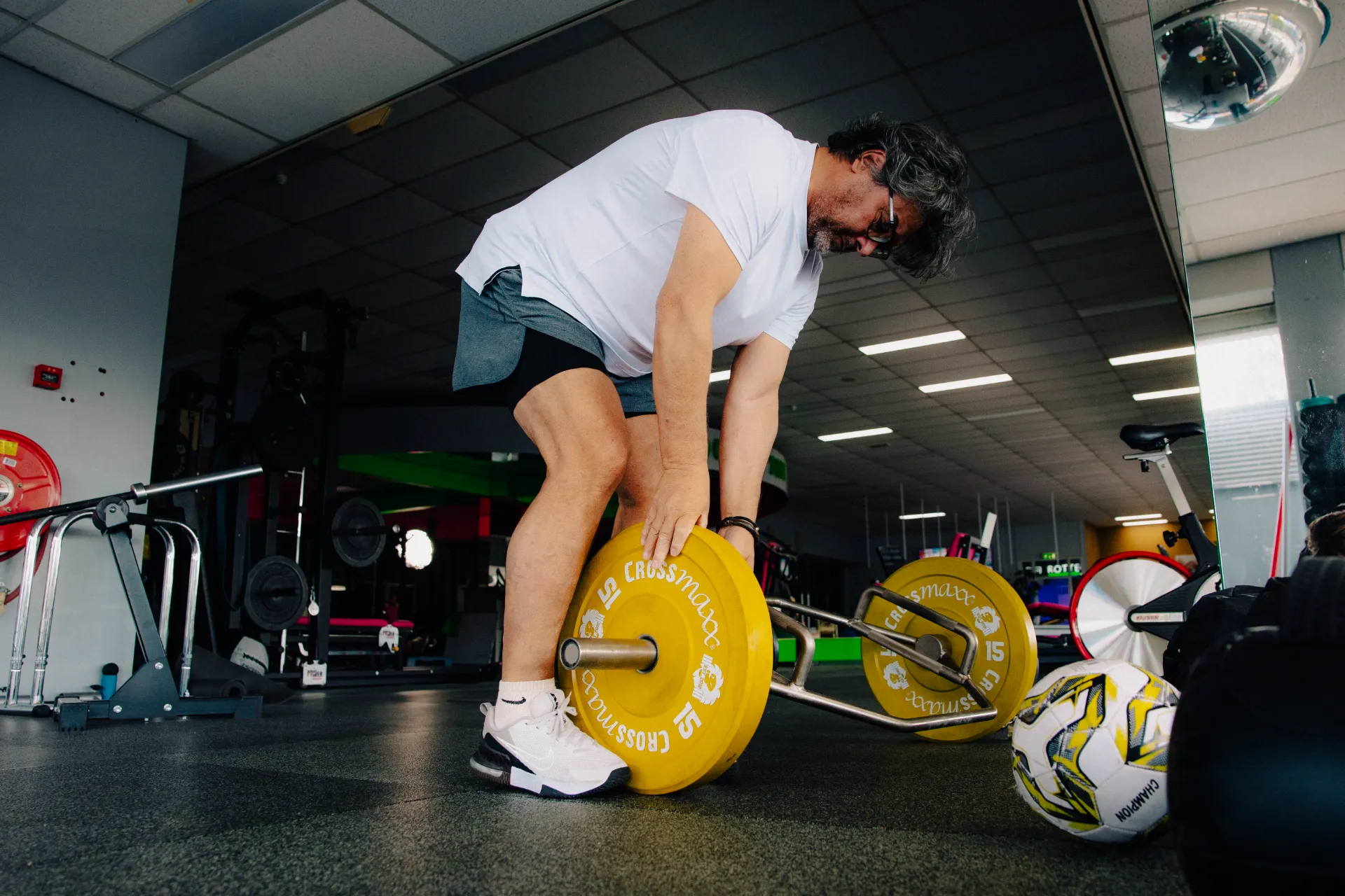 Sporter tilt een barbell met gekleurde schijven