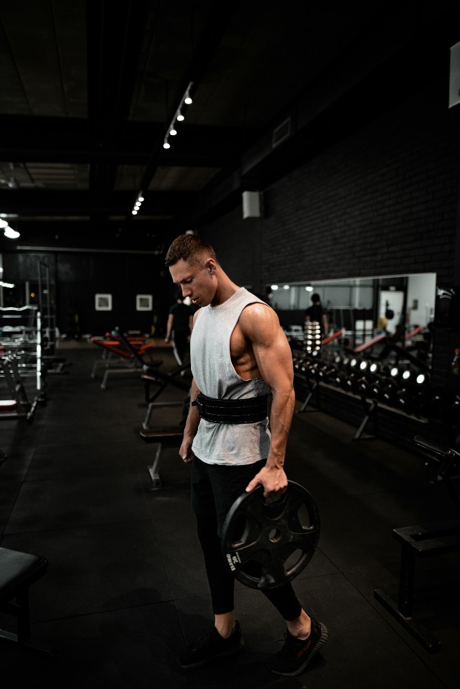  A man in a gym looking down at his phone, holding a water bottle. Quote: “I used to dread working out. Now it’s the best part of my day…” – Software Engineer.