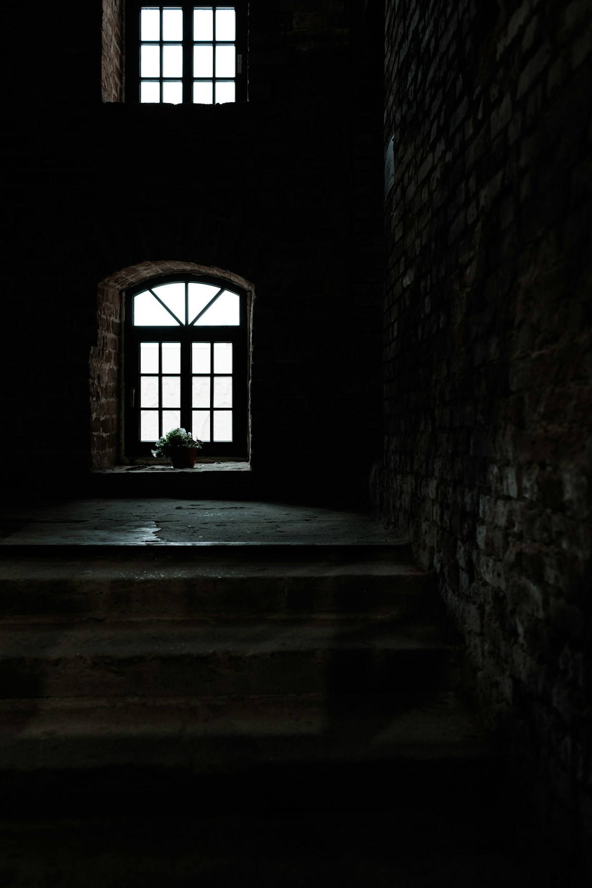 Window light falls into a shadowy historic brick corridor