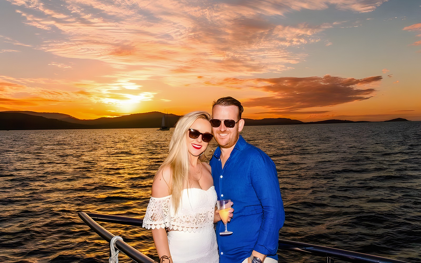 Couple enjoying a sundowner cruise at sunset, Airlie Beach.