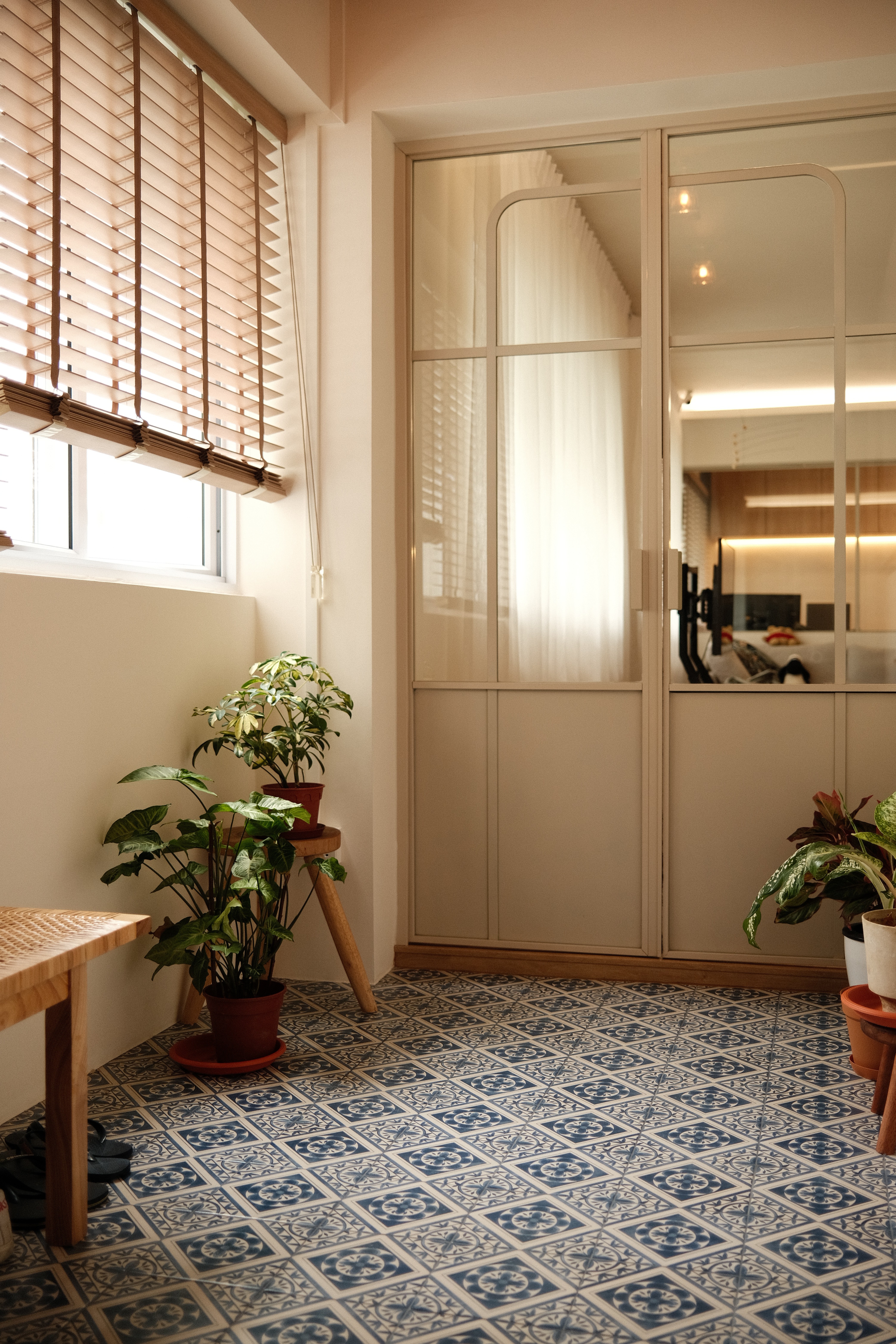 A light-filled transitional space defined by patterned tiles, soft neutrals, and greenery—where function meets quiet charm.