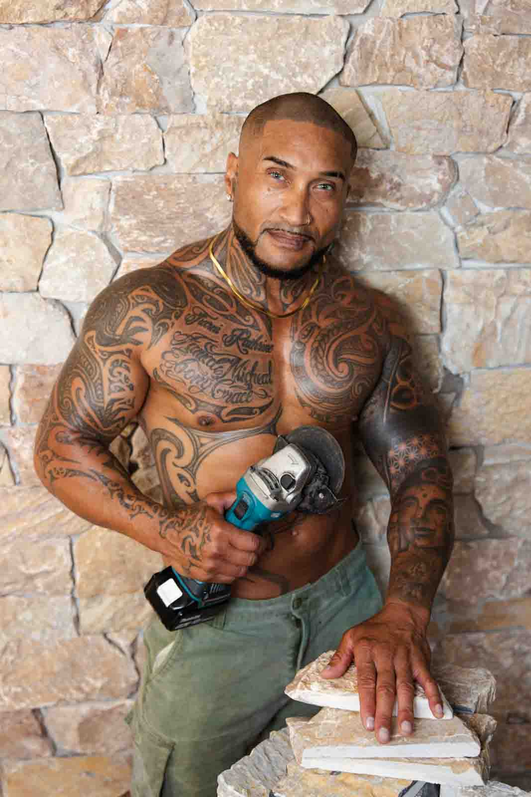 Shirtless man cutting tiles