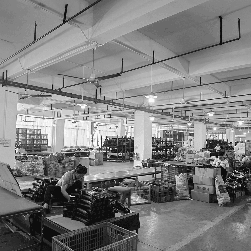 Workers assembling office chair components on a bright, industrial manufacturing floor.