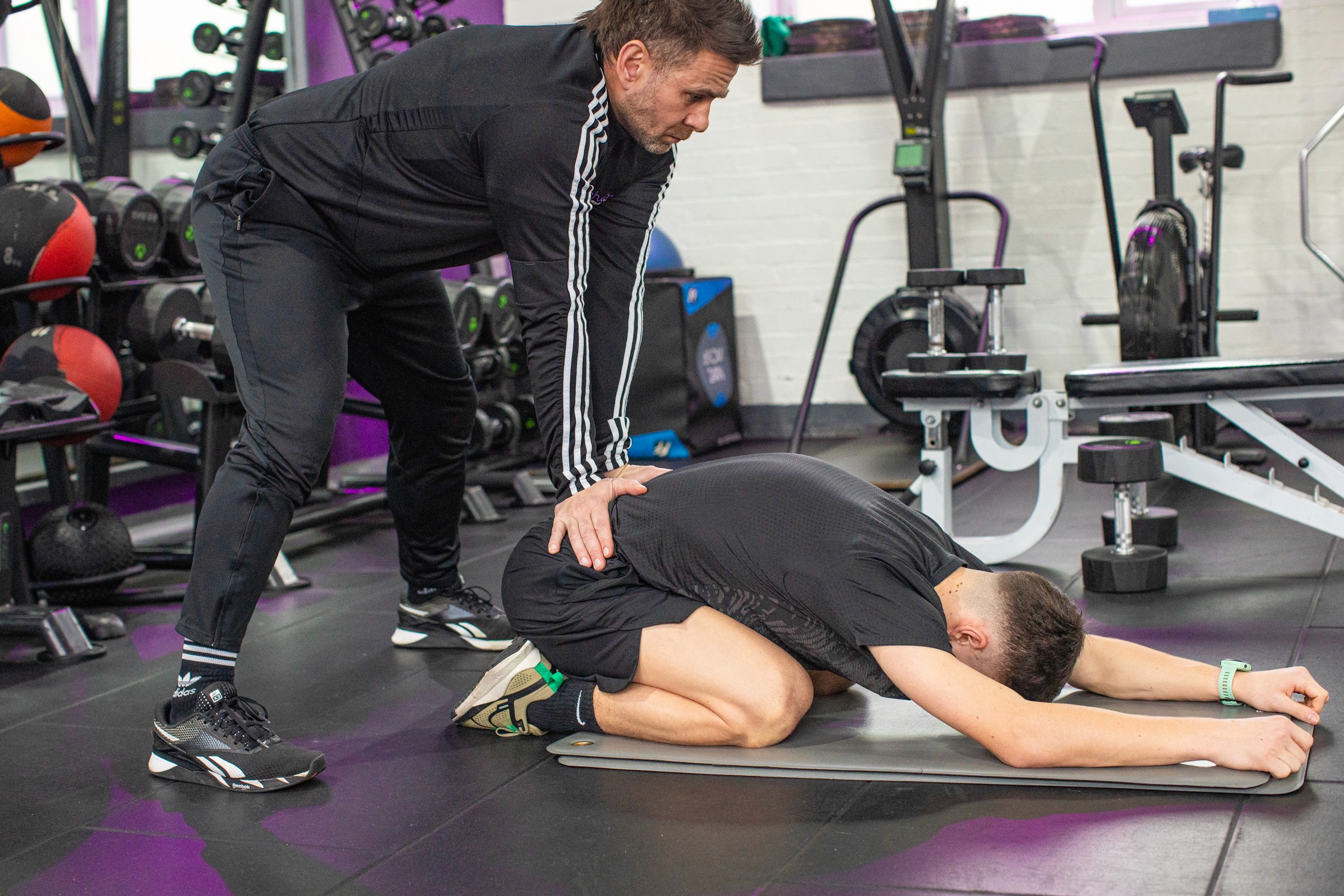 Gym-goer is demonstrating the child's pose stretch as a flexibility exercise for the lowe back.