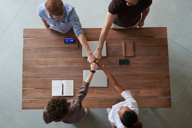 Bird's eye view of four people fist bumping over a table