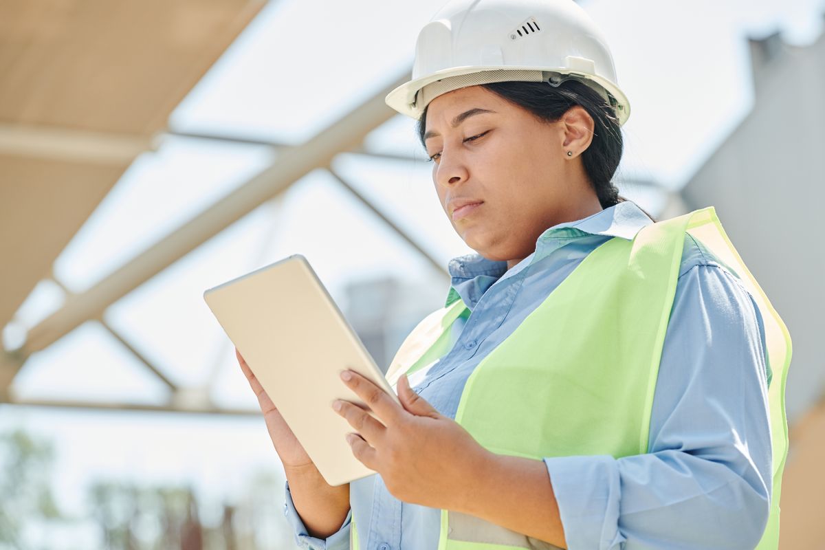 Technicien de maintenance utilisant une application de rapport d'intervention sur tablette dans un local technique
