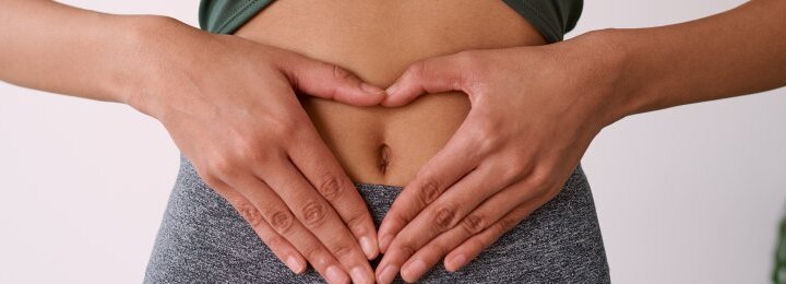 Persona con las manos en forma de corazón sobre el abdomen para representar la microbiota intestinal.