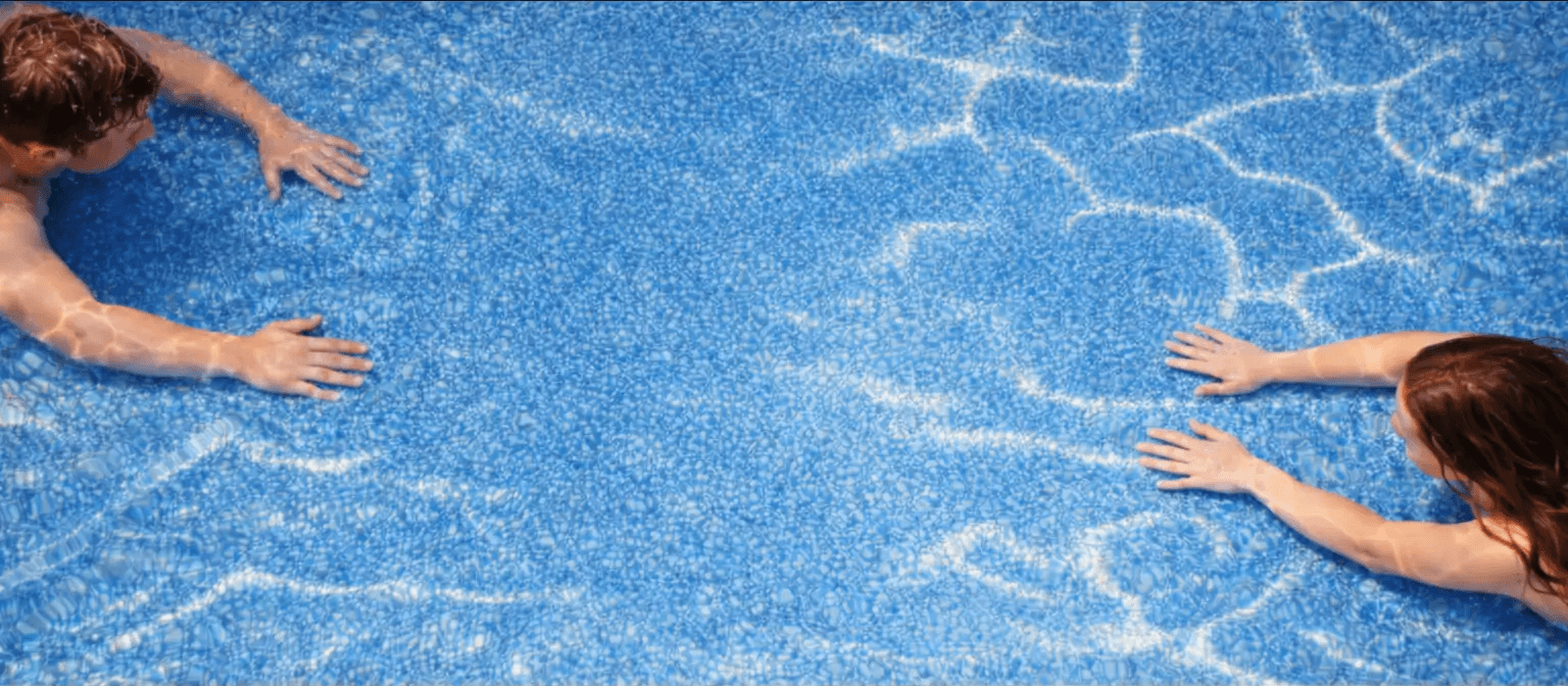 Couple swimming towards eachother in luxury backyard pool