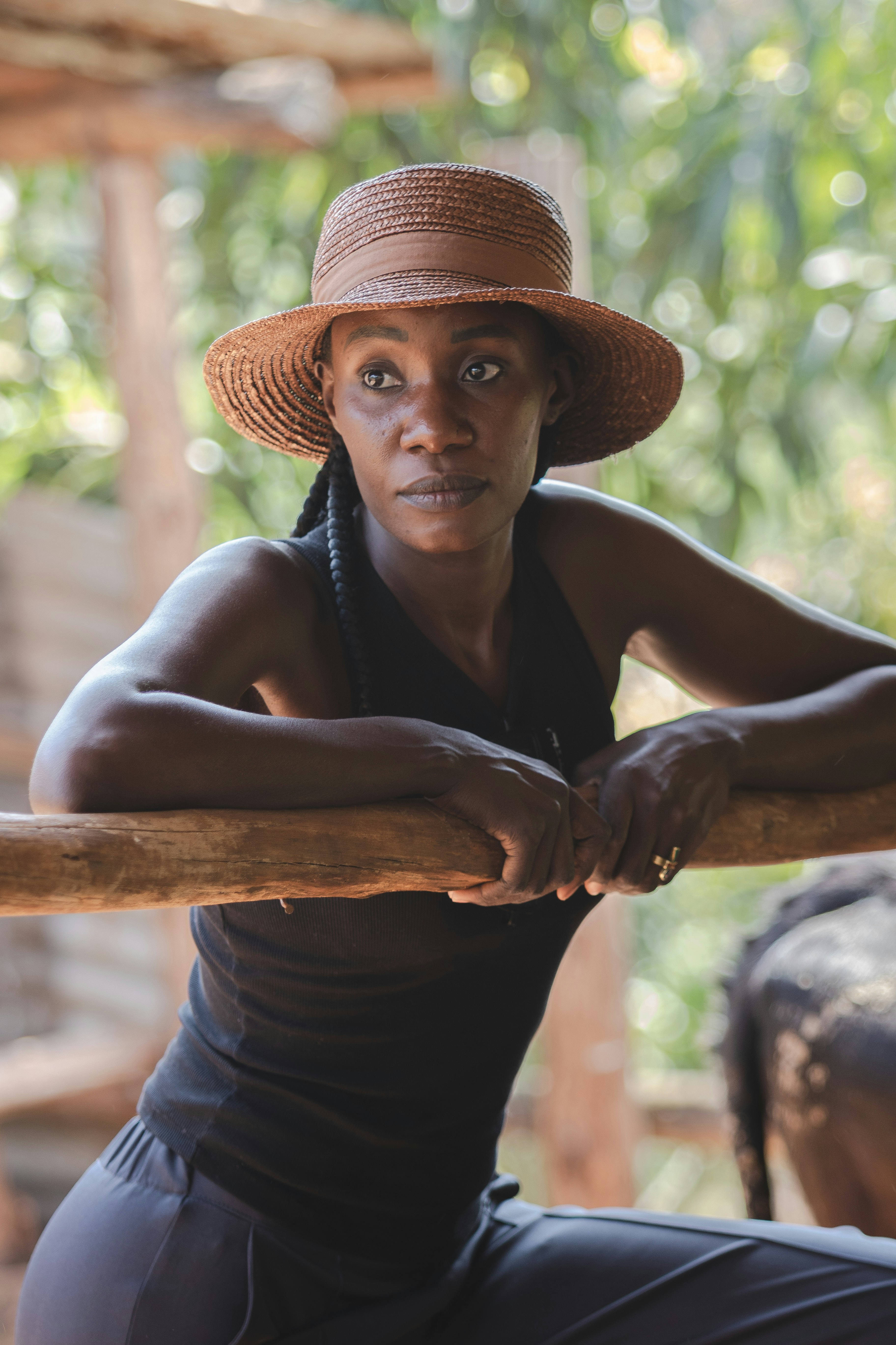 A woman in a straw hat leaning on a wooden pole