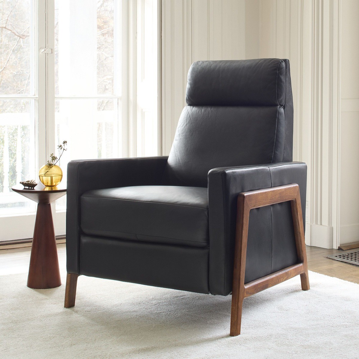 Black leather Spencer recliner with wooden frame, placed in a bright room