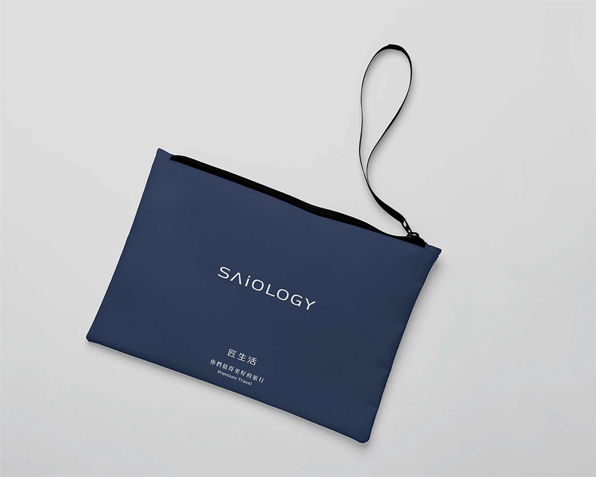 這張圖展示了匠生活的深藍色收納袋,袋子上印有「SAiOLOGY」品牌標誌、中文「匠生活」字樣及「您們值得更好的旅行」的字樣,並配有黑色拉鏈和手提帶。