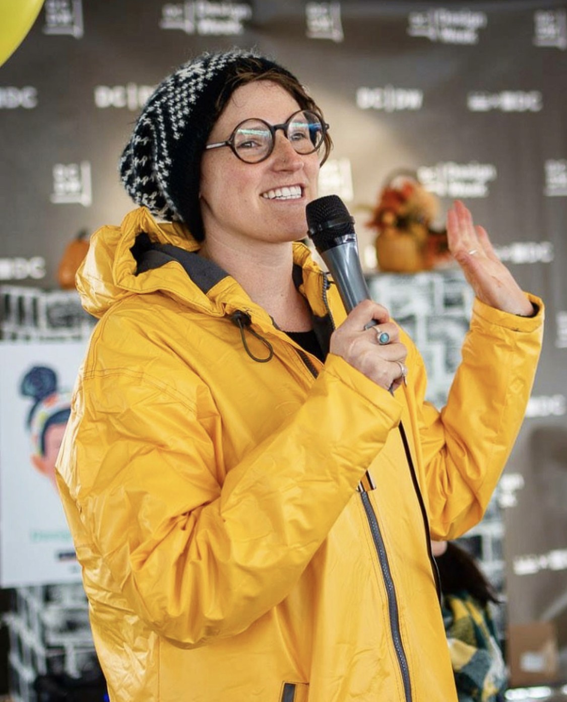 Liz Rose holding a microphone introducing speakers at a DC Design Week event in Washington, DC.