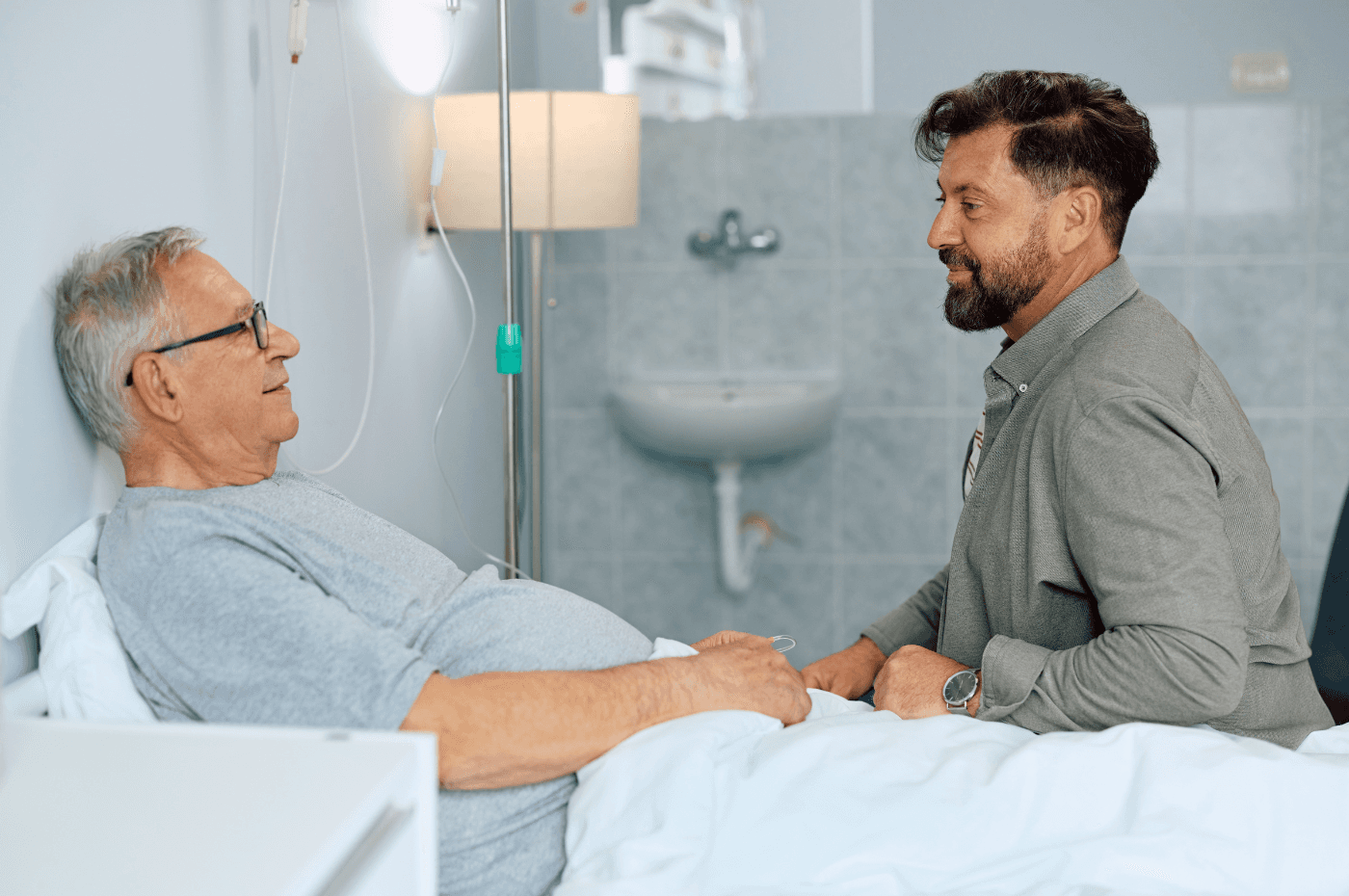 Happy man visiting his senior father in the hospital