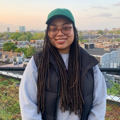 A portrait photo of Kim Wells, a medium brown-skilled woman with long hair and glasses dressed in outdoor wear. 