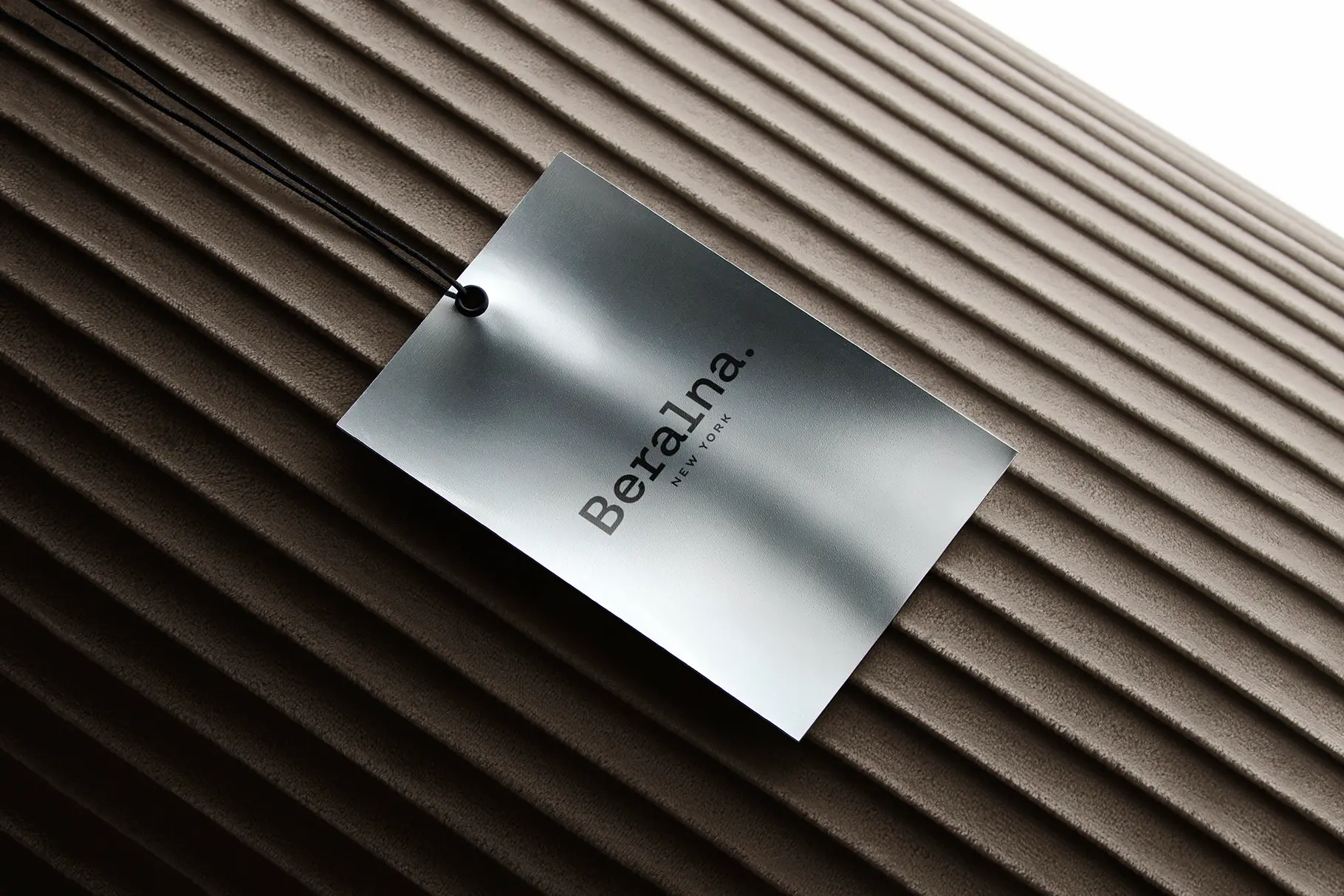 Premium metallic tag mockup on ribbed surface with realistic lighting and luxury branding details.