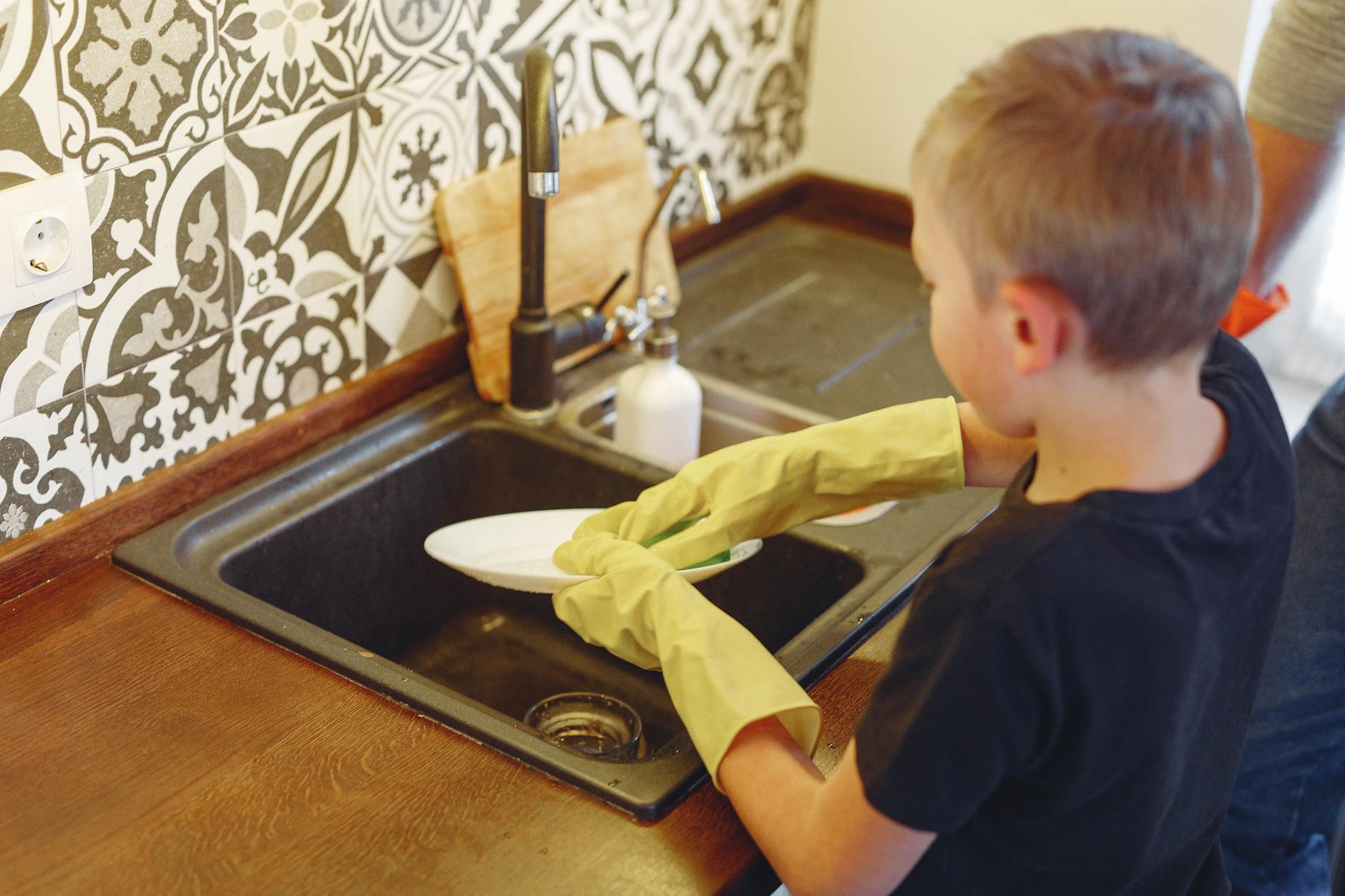 A parent and child organizing a homeschool station with labeled wooden bins and a small indoor plant.
