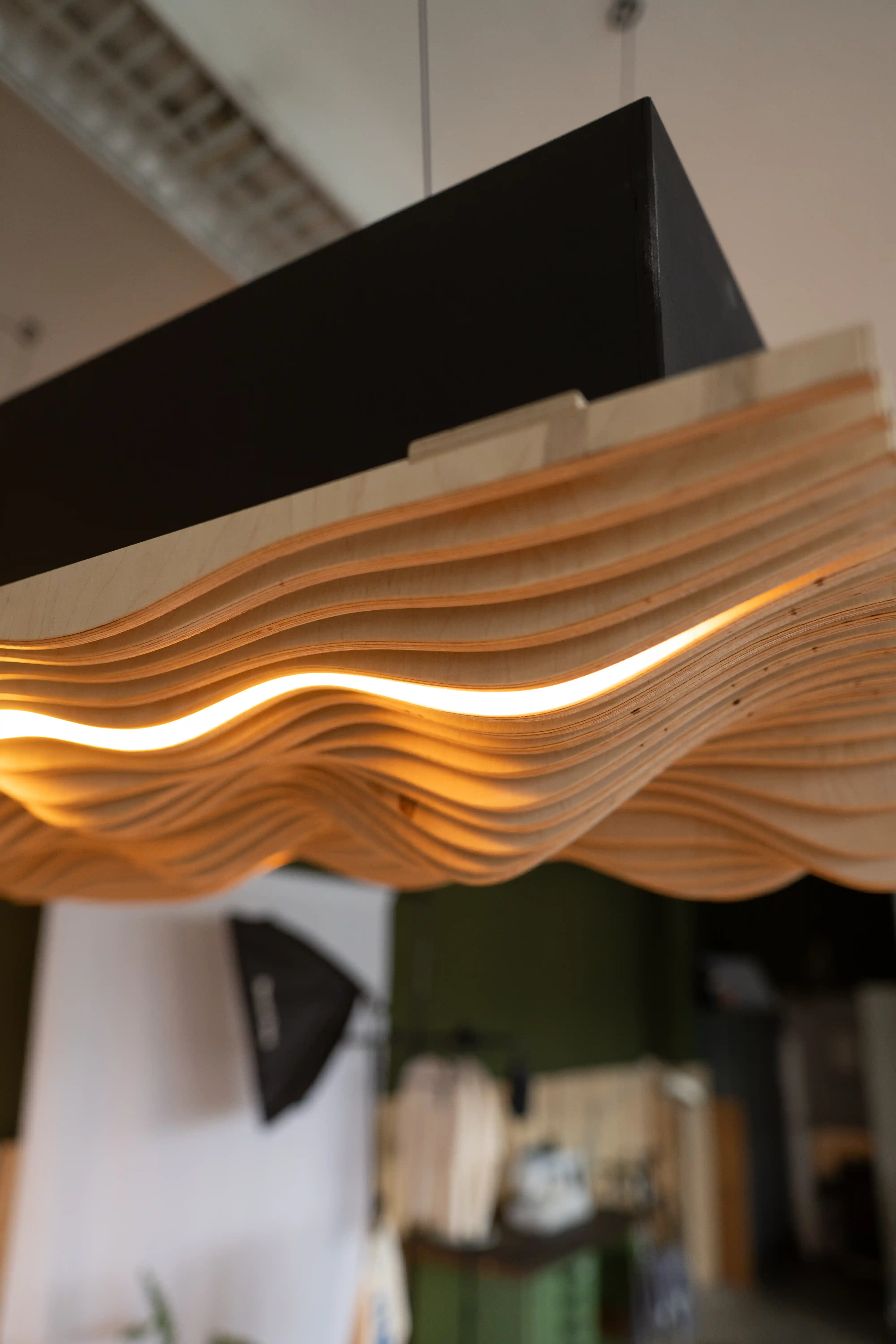 Detailaufnahme der Wellenstruktur der Akustiklampe aus Holz, zeigt Material und handgefertigte Verarbeitung