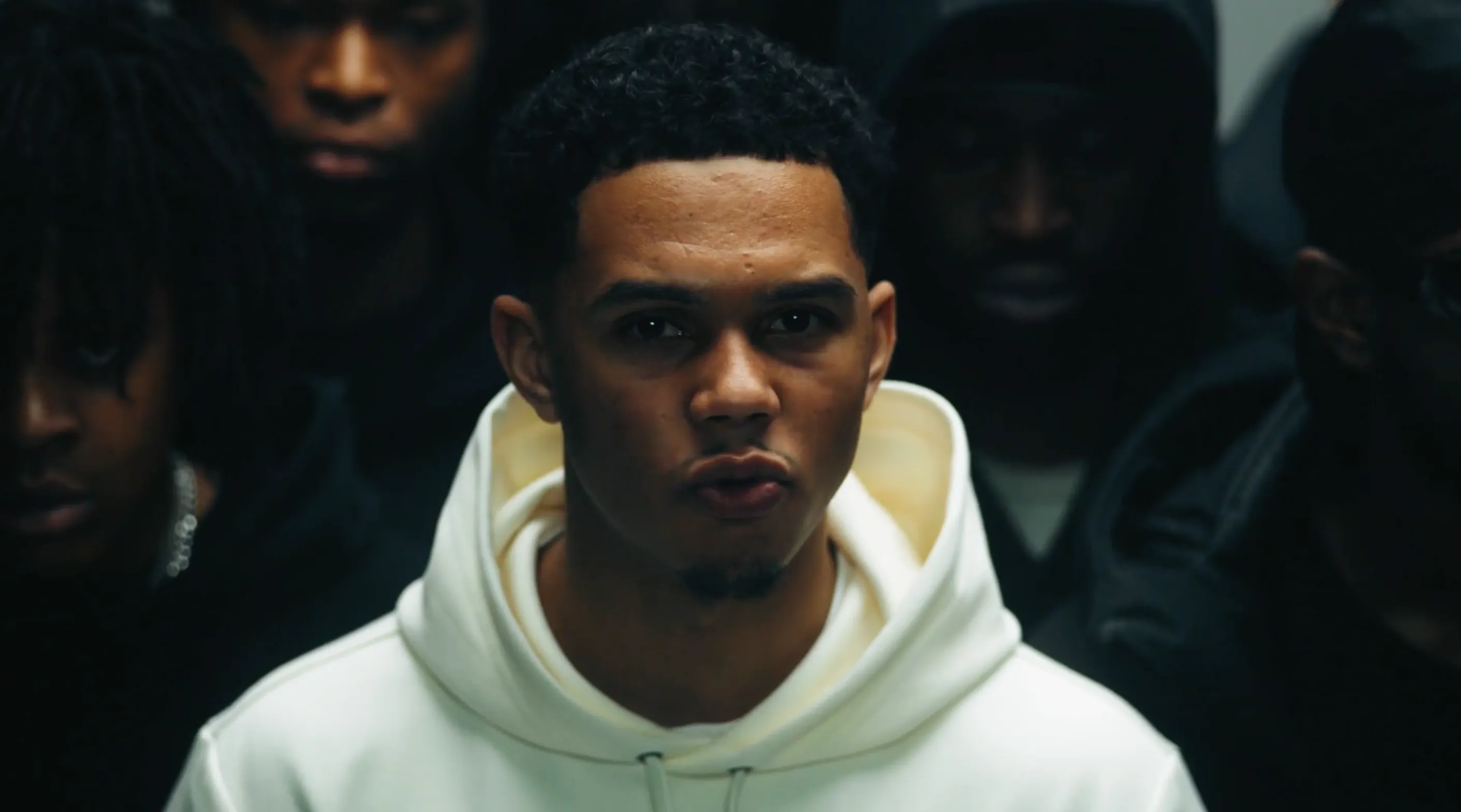 A man in a white tracksuit looking into the camera