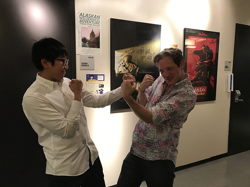 photo of two men playing fighting in a hallway