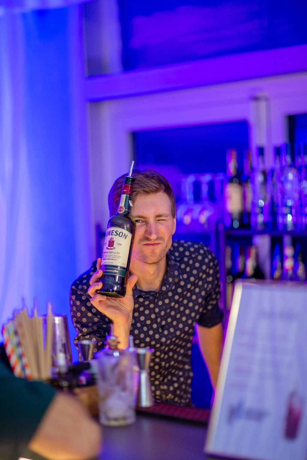 Barman na weselu pokazuje sztuczki barmańskie przed zgromadzonymi gośćmi podczas pokazu barmańskiego