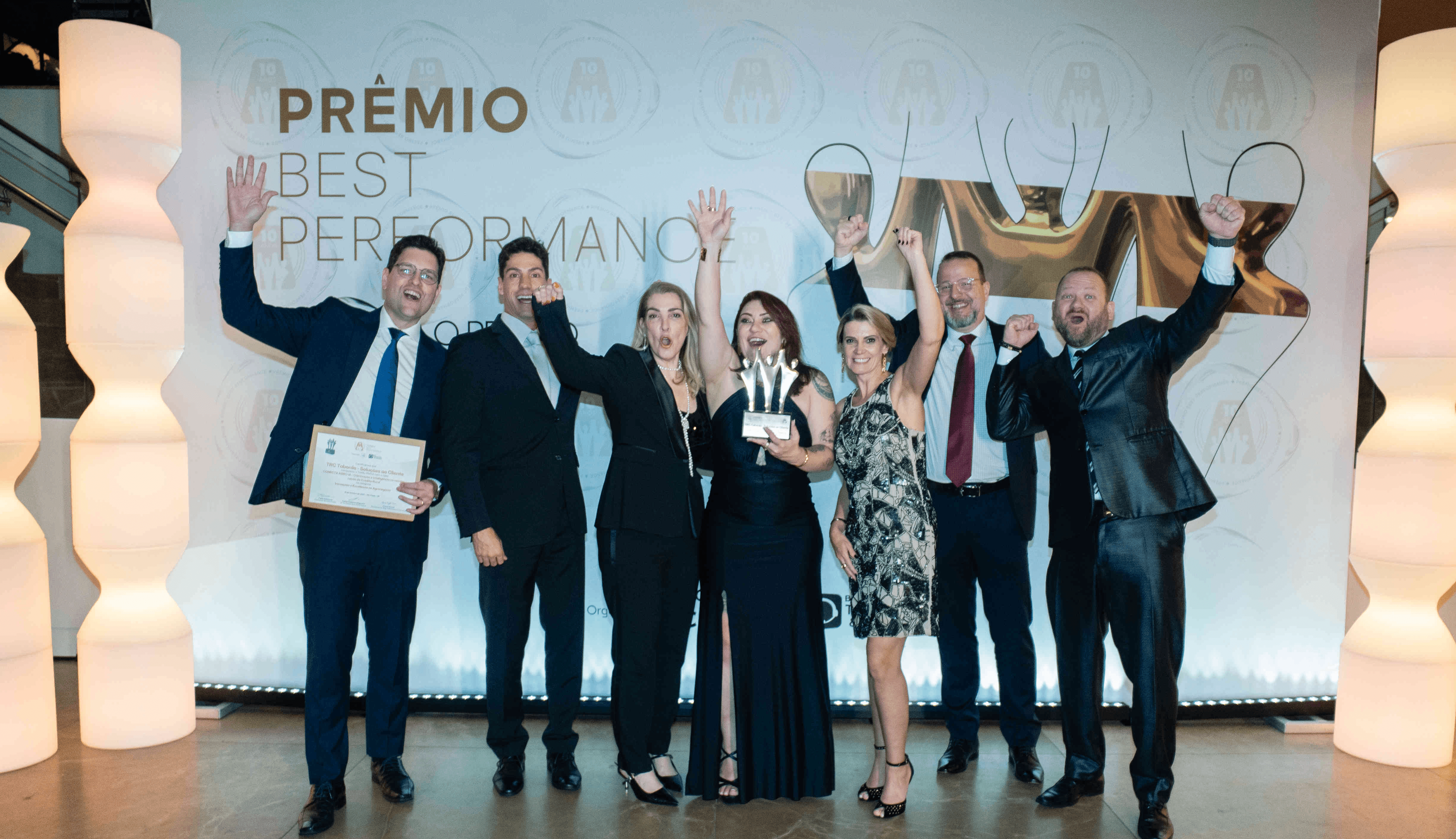 Executivos da TRC Taborda posando com troféu ouro e certificado no palco do Prêmio Best Performance 2025