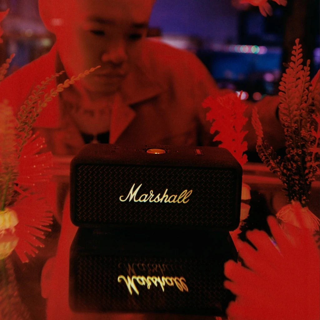 Person sitting next to black bluetooth speaker