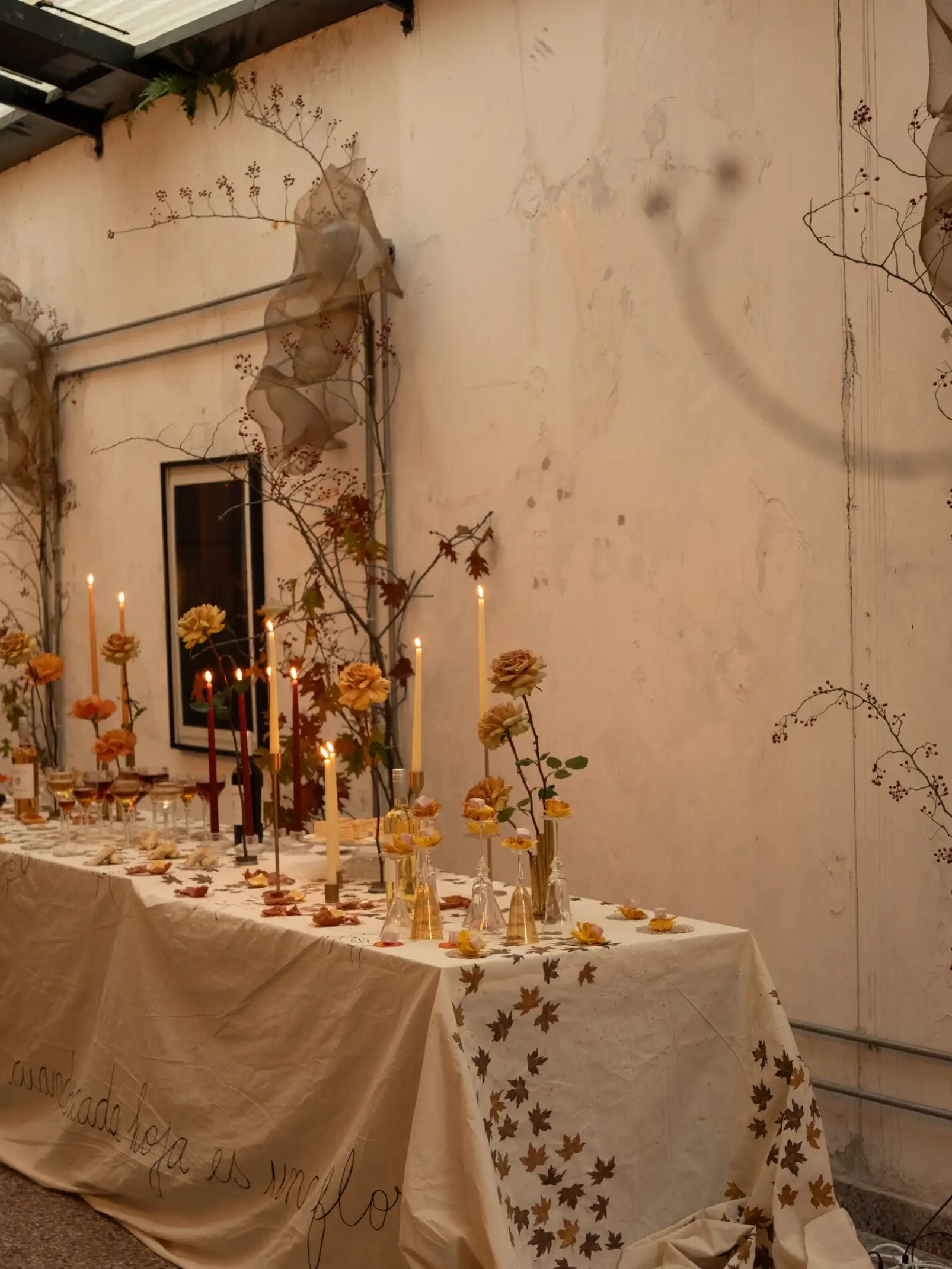 Mesa larga con rosas amarillas y velas para experiencia gastronómica de otoño, generando un ambiente elegante y poético.