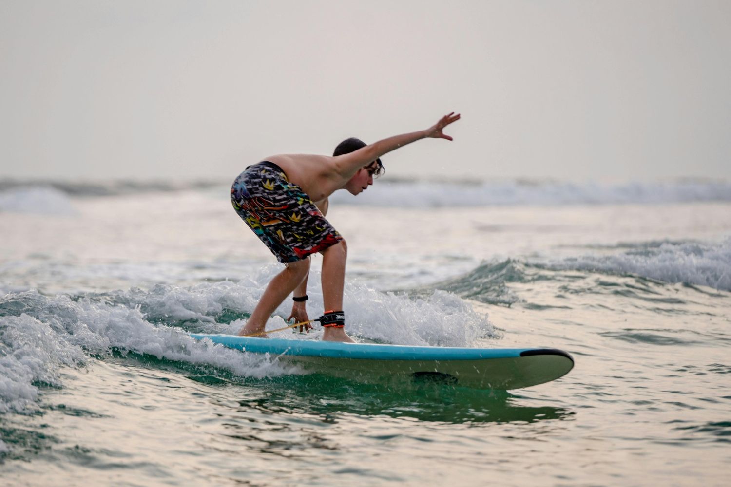 Surfer balancing on a board in tropical sun-drenched water — surfboard rental in South Asia